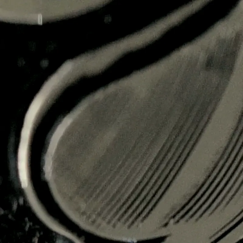 Gota de metal líquido negro sobre grano, en penumbra