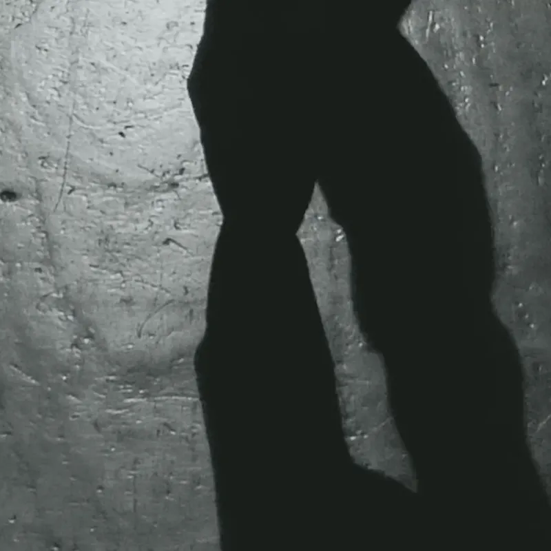 Silueta masculina recortada contra un muro de hormigón iluminado
