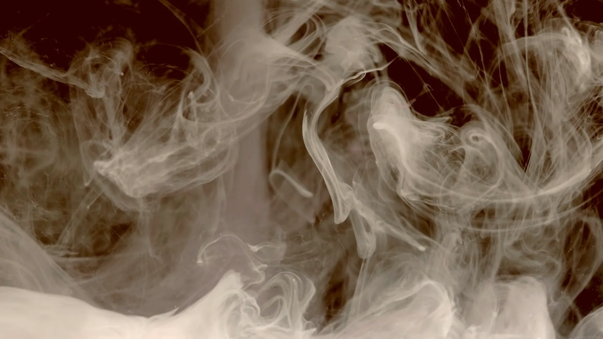 Humo girando en penumbra bajo luz ámbar