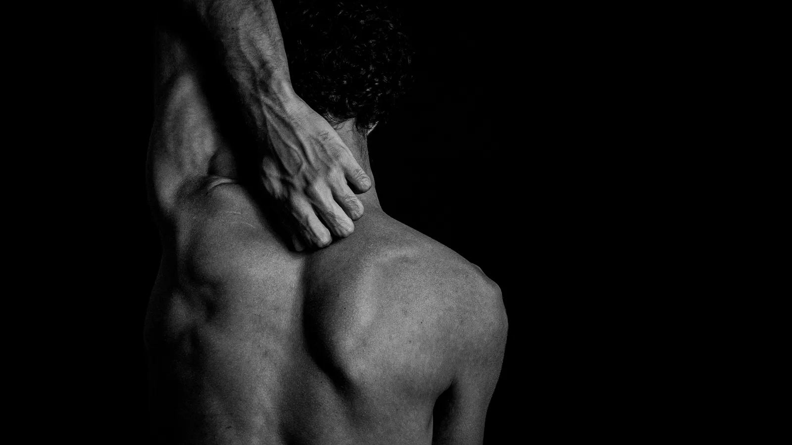Espalda masculina en blanco y negro con una mano en la nuca